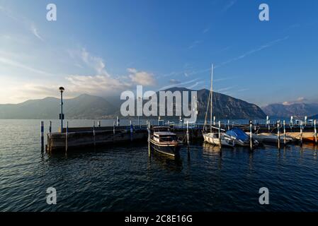 Italia, Lombardia, Barche ormeggiate al molo sul lago d'Iseo al tramonto Foto Stock