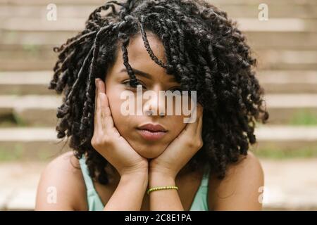Ritratto di giovane donna riccia con le mani sul mento Foto Stock