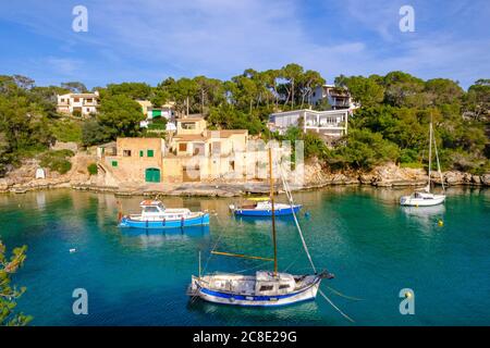 Spagna, Maiorca, Santanyi, barche da pesca ormeggiate di fronte al villaggio costiero in estate Foto Stock