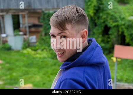 Primo piano ritratto di un giovane ragazzo sorridente e bello in una giacca viola Foto Stock