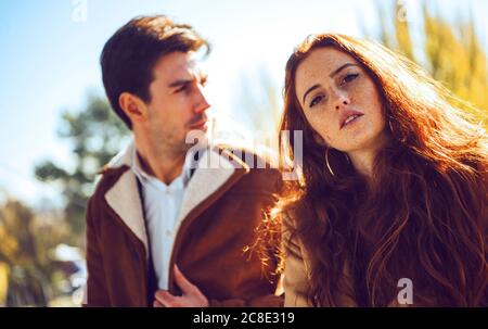 Giovane donna con uomo pensieroso in background durante la giornata di sole Foto Stock