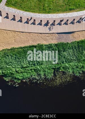 Russia, Tikhvin, uomo in bicicletta sul lungomare con lettini, vista aerea Foto Stock