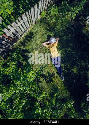 Vista aerea della donna mid adulta che riposa su terra erbosa in giardino Foto Stock