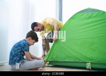 Padre e figlio che mettono la tenda a casa Foto Stock