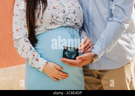 Una coppia in attesa di scattare foto ecografiche mentre si trova all'aperto Foto Stock