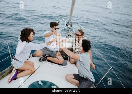Spensierate gli amici che tostano bicchieri di birra mentre si siedono a vela dentro mare