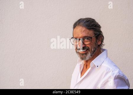 Felice uomo maturo che indossa occhiali contro parete grigia Foto Stock
