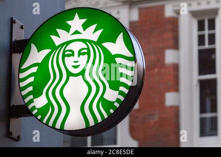 Un cartello illuminato che mostra il logo del caffè Starbucks sul lato di un edificio Foto Stock