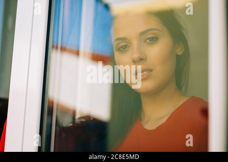 Primo piano di una giovane donna vista attraverso la porta di vetro Foto Stock