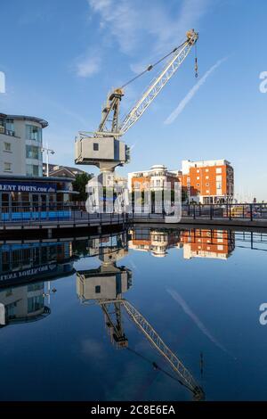 Una vecchia gru portuale che riflette in acqua a Gunwharf Quays Portsmouth Foto Stock