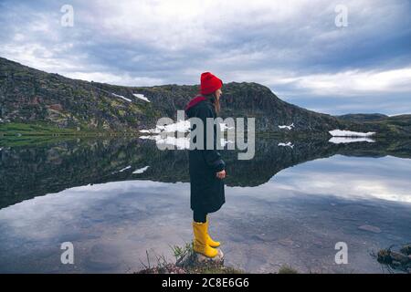 Donna in piedi sulla roccia nel lago di Teriberka, Murmansk Oblast, Russia Foto Stock