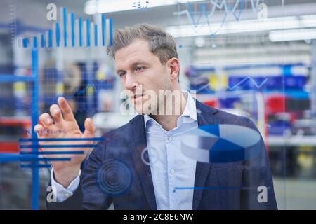 Grafici a contatto con il supervisore maschile sul vetro nell'industria Foto Stock