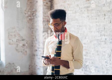 Elegante giovane uomo che usa lo smartphone in loft Foto Stock
