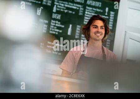 Premuroso proprietario maschile che guarda lontano mentre si trova in una caffetteria Foto Stock