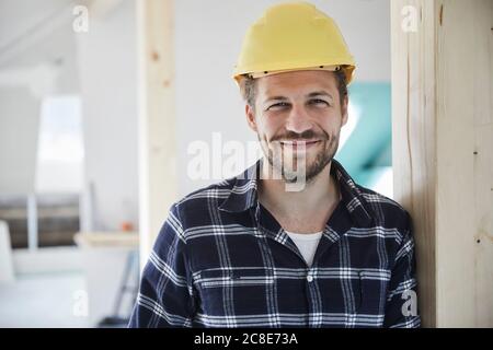 Ritratto di un operaio di smilling che indossa un elmetto su un cantiere Foto Stock