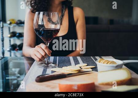 Giovane donna che tiene il verricello mentre si siede al tavolo da pranzo Foto Stock