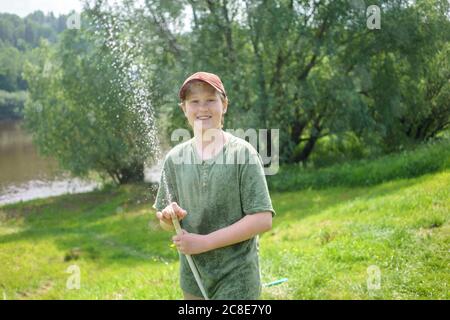 Ragazzo sorridente che tiene il tubo mentre si trova in piedi nella foresta Foto Stock