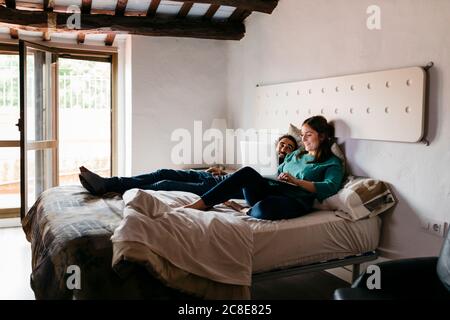 Coppia che guarda un film seduto a letto a casa Foto Stock