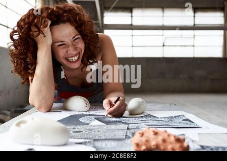 Primo piano di una donna allegra che disegna schizzi sul banco da lavoro in studio Foto Stock