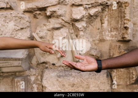 Mani di coppia che si raggiungono l'un l'altro contro muro di pietra Foto Stock