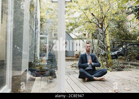 Uomo d'affari che pratica yoga in cortile Foto Stock