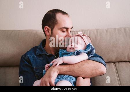 Padre che porta la bambina addormentata sul divano a casa Foto Stock