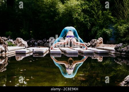 Donna che allunga i muscoli mentre si esercita al parco pubblico Foto Stock