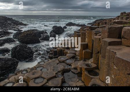 Le onde si infrangono sul Selciato del Gigante, Causeway Coast, County Antrim, Irlanda del Nord Foto Stock