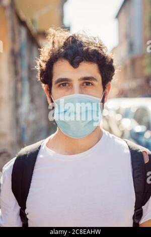 Ritratto di giovane uomo che indossa una maschera in piedi all'aperto Foto Stock