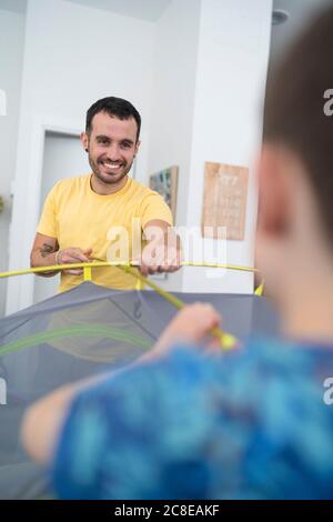 Padre e figlio che mettono la tenda a casa Foto Stock