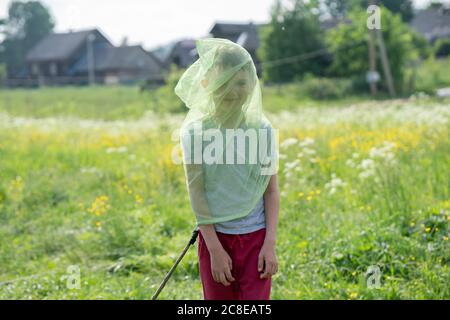 Ragazzo giocoso che indossa la rete a farfalla mentre si trova su terra erbosa Foto Stock