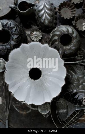 Collezione di vecchi utensili da cucina rustici tra cui teglie, teglia da forno, frusta e imbuto Foto Stock