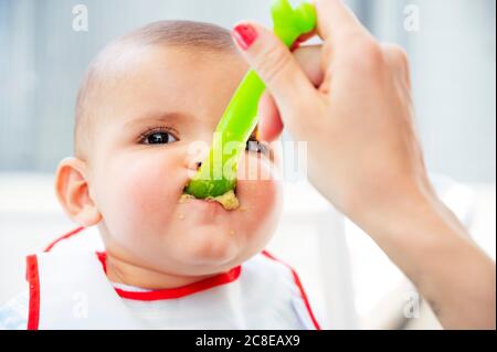 Mano tagliata di madre che alimenta il figlio carino a casa Foto Stock