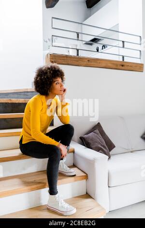 Giovane donna pusiva seduta sulle scale a casa Foto Stock