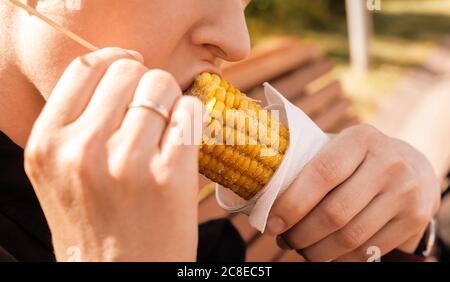 Donna caucasica che mangia mais sul closeup di pannocchie. Foto Stock