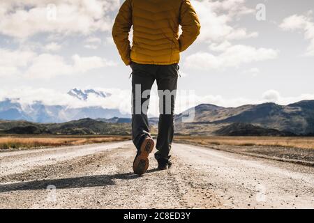 Sezione bassa di uomo maturo che cammina su strada sterrata al Parco Nazionale Torres del Paine, Patagonia, Cile Foto Stock