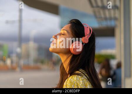 Giovane donna rilassata che ascolta musica in città