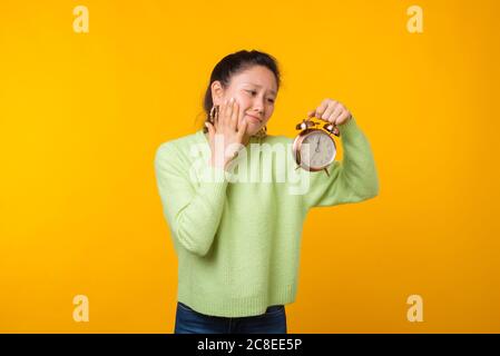 OH guardalo. La ragazza tiene una sveglia su sfondo giallo. Foto Stock