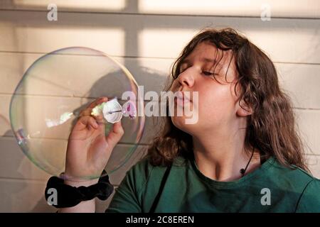 Umea, Norrland Svezia - 29 giugno 2020: La giovane ragazza soffia una bolla enorme di sapone Foto Stock