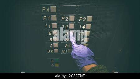 Pulsante di sollevamento con mano che indossa guanti medici per l'igiene, toccando la superficie pubblica, cura personale delle mani per l'igiene del coronavirus COVID-19 Foto Stock