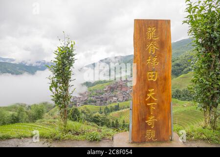 Pittoresche risaie a terrazze e case di villaggio a Jinkeng, Longji, Guangxi, Cina durante una giornata torbida e nuvolosa con occasionali precipitazioni Foto Stock