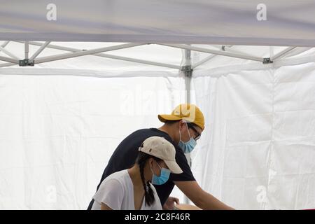 I venditori ambulanti mascherati lavorano in uno stand di cibo al mercato agricolo del sabato nel centro di Portland, Oregon, il 18 luglio 2020, in mezzo alla pandemia del coronavirus. Foto Stock