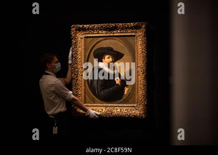 Un assistente alla galleria si pone accanto al Ritratto di un uomo, a mezza lunghezza in nero con un ampio cappello nero brimmed e una ruff bianca, tenendo i suoi guanti con un ovale dipinto da Frans Hals, 1635, Olio su tela con una stima di 2-3 milioni di sterline durante un'anteprima stampa a Sotheby's a Londra prima della vendita "da Rembrandt a Richter" il 28 luglio. Foto Stock