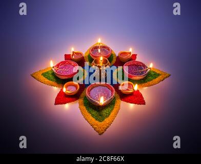 Happy Diwali, lampade diya accese su rangoli colorati Foto Stock