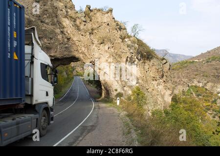 Un arco di pietra naturale forma un tunnel vicino al bacino idrico di Artsvanik sulla rotta da Goris al confine iraniano nell'Armenia meridionale. Foto Stock