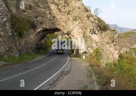 Un arco di pietra naturale forma un tunnel vicino al bacino idrico di Artsvanik sulla rotta da Goris al confine iraniano nell'Armenia meridionale. Foto Stock