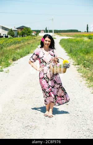 Felice Countrygirl a piedi e tenendo cesto con fiori Foto Stock