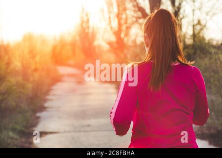 Torna di donna che corre, godendo di una giornata estiva nel parco Foto Stock