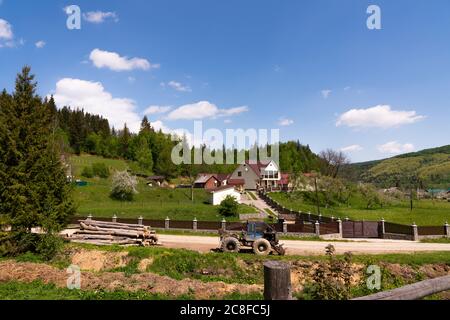 Nuova casa di famiglia in montagna, trattore su strada Foto Stock