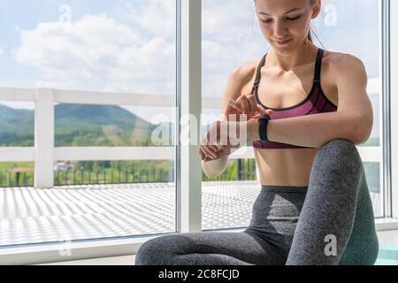 Vista ritagliata della donna atletica che guarda l'orologio intelligente Foto Stock